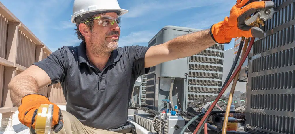 person in white hardhat working on HVAC unit