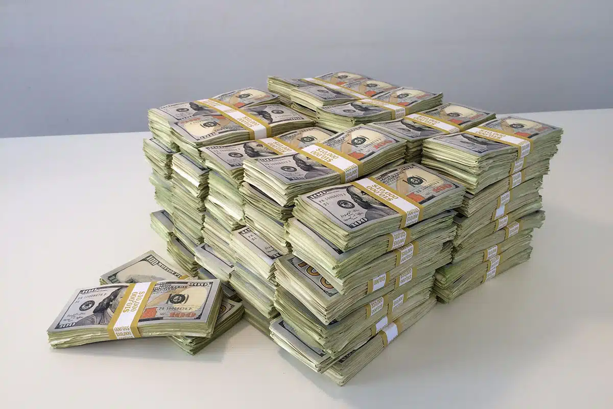 Multiple stacks of American money sit on a white table